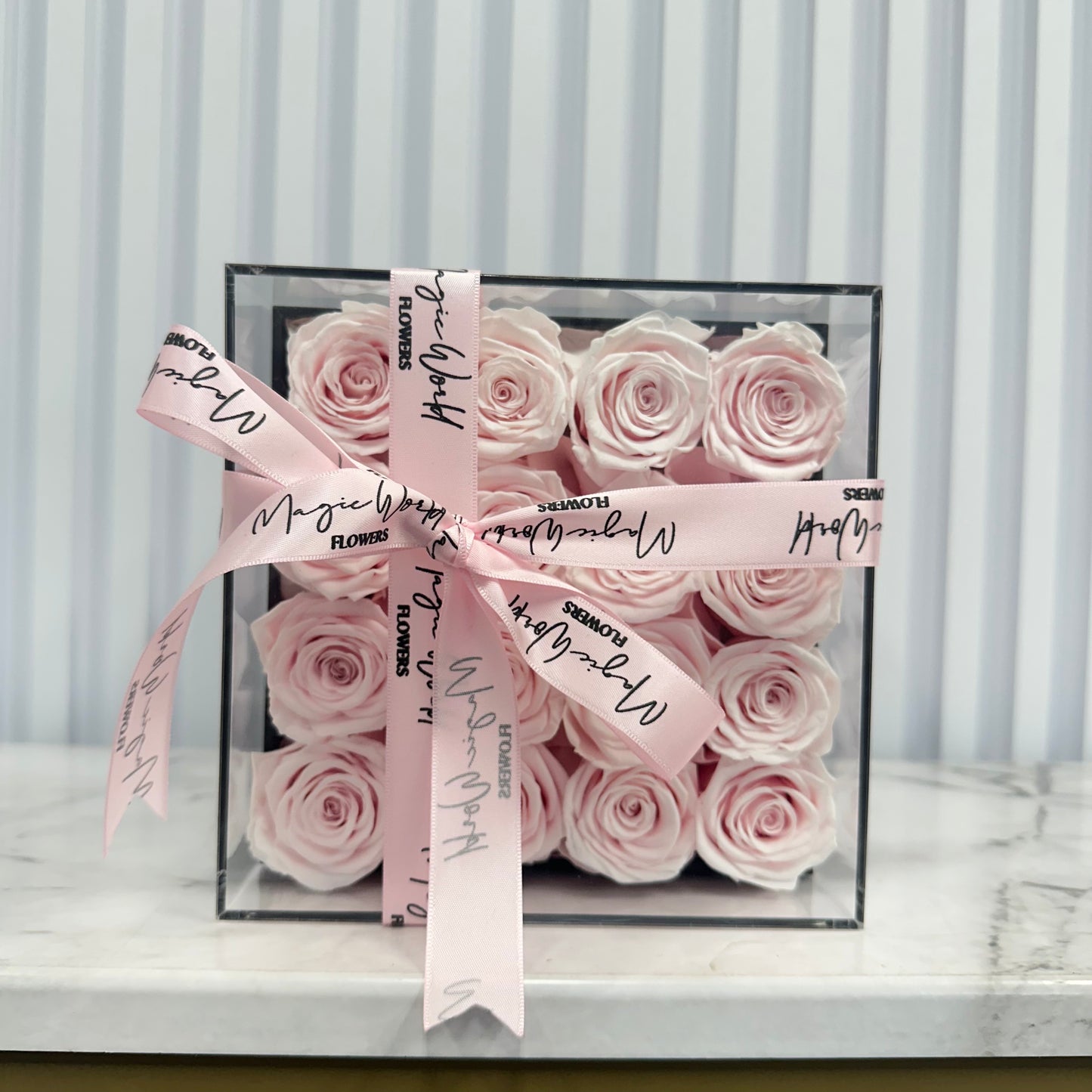 Delicate light pink preserved roses beautifully arranged in an acrylic box, a timeless gift for birthdays, anniversaries, and love celebrations in Grapevine, Carrollton, and Hurst.